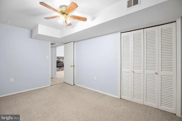 an empty room with closet and a ceiling fan