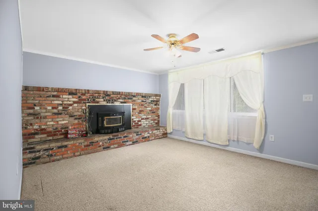 an empty room with windows and fireplace