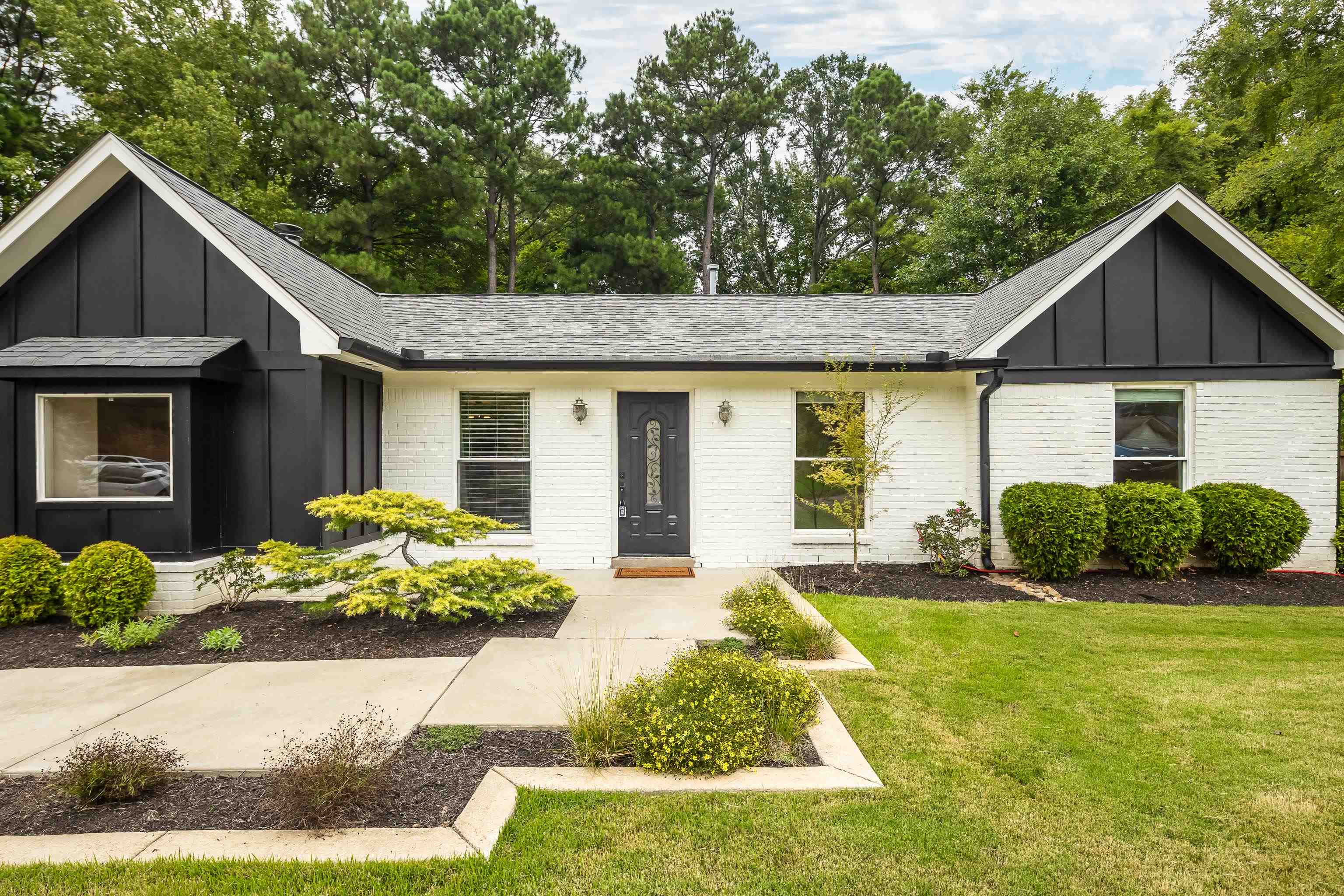 a front view of a house with a yard and potted plants