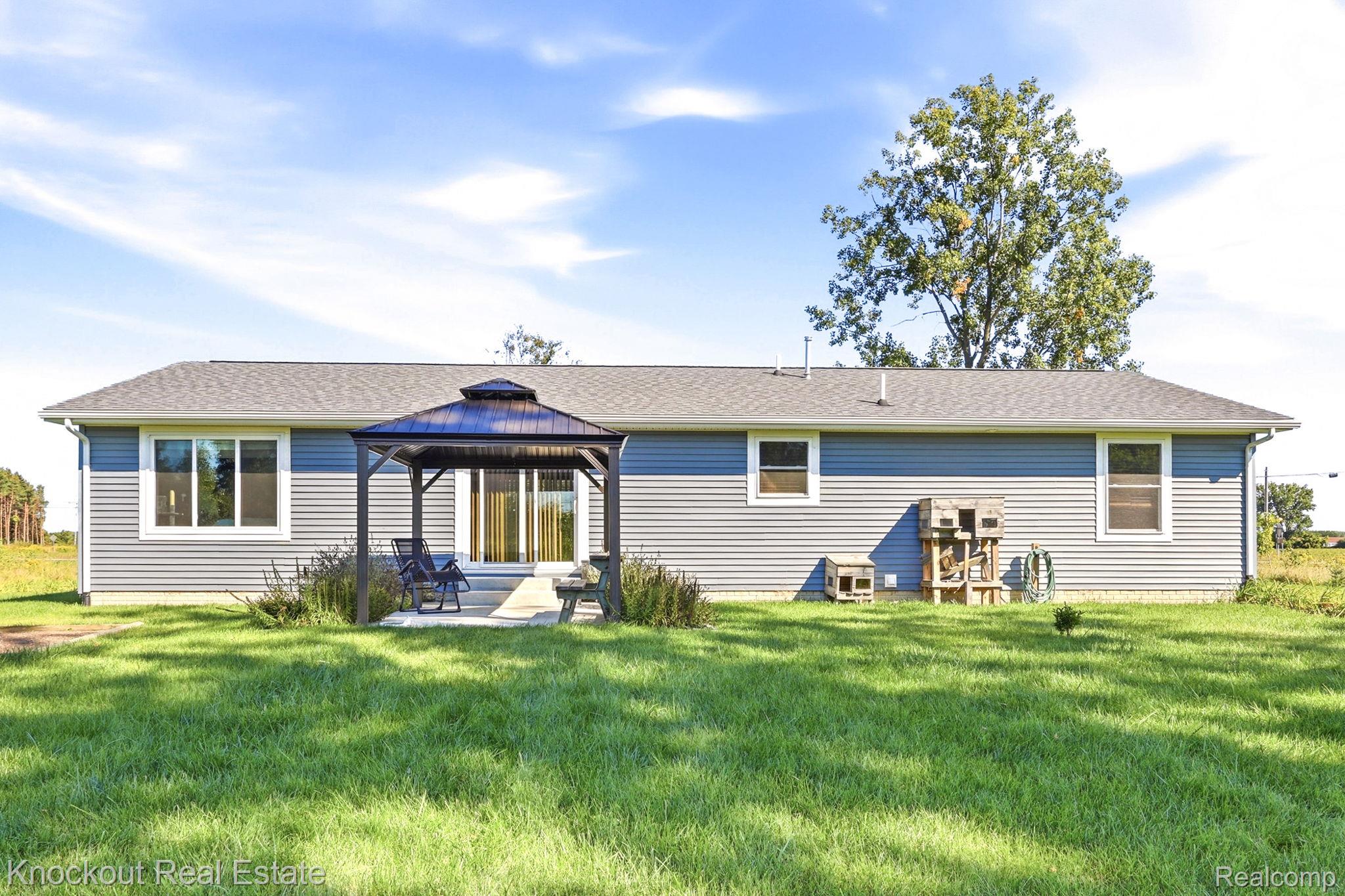 5727 Mackinaw Road Saginaw, MI 48604 - Photo 37 of 60 Expansive green lawn with a gray siding exterior, a gray shingled roof, a dark metal gazebo, and a concrete patio