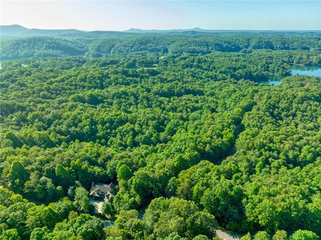 101 Wake Robin Drive Sunset, SC 29685 - Photo 2 of 8 An aerial perspective reveals a secluded estate nestled within a dense, verdant forest, bordered by distant mountains and a serene lake.