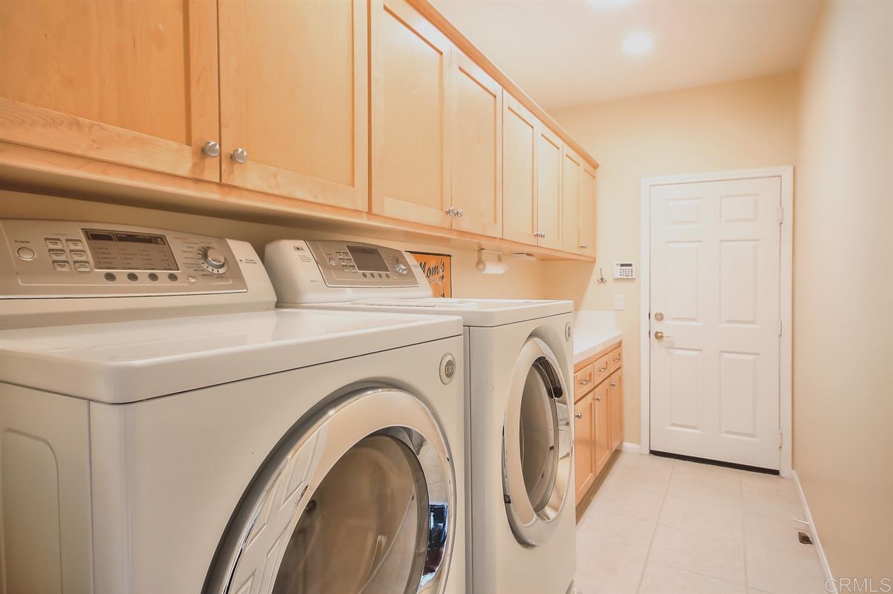 1424 Ridgeway Street Oceanside, CA 92054 - Photo 22 of 25 Laundry with sink basin, built-ins for storage and a folding area too. Door is direct access to the four car garage.