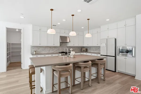 a kitchen with stainless steel appliances granite countertop a table chairs stove a sink and a refrigerator