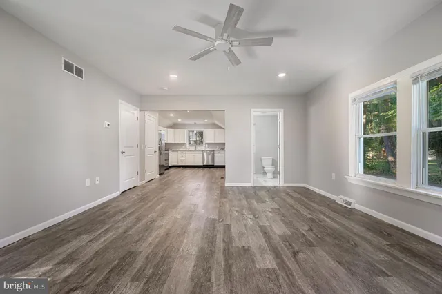 a view of empty room with wooden floor and fan