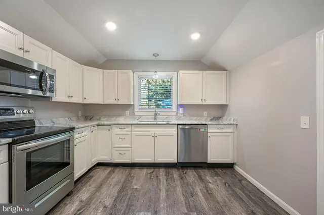 a kitchen with granite countertop white cabinets stainless steel appliances and a sink