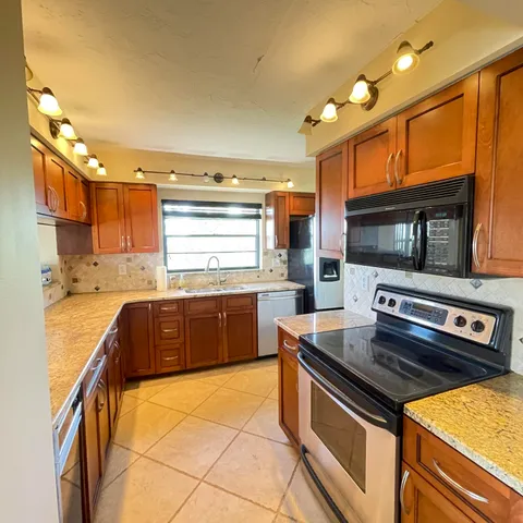 a kitchen with stainless steel appliances granite countertop a sink stove and microwave