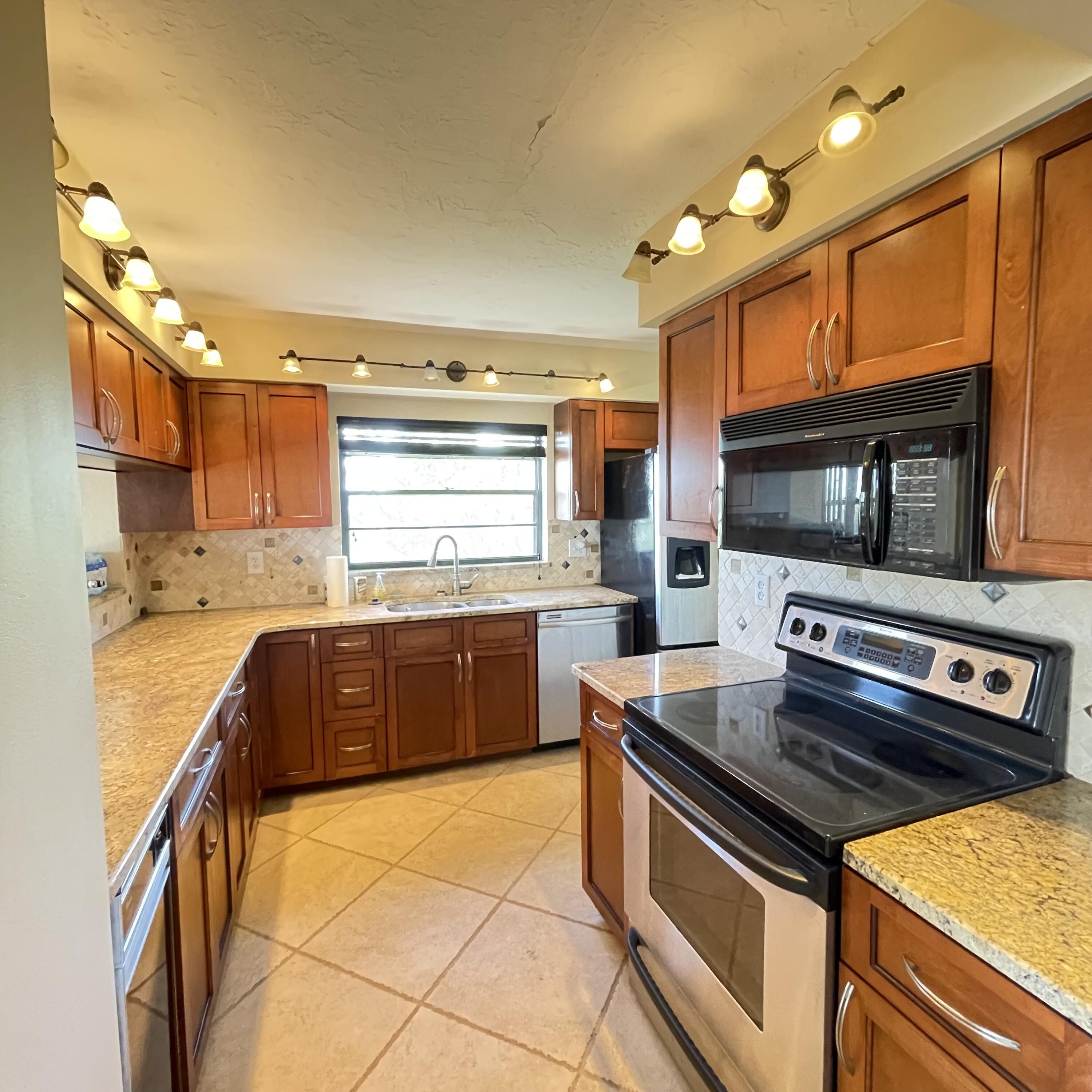 1540 Riverside Drive, Unit 14 Titusville, FL 32780 - Photo 11 of 29 a kitchen with stainless steel appliances granite countertop a sink stove and microwave