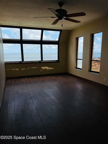 a view of empty room with wooden floor and fan
