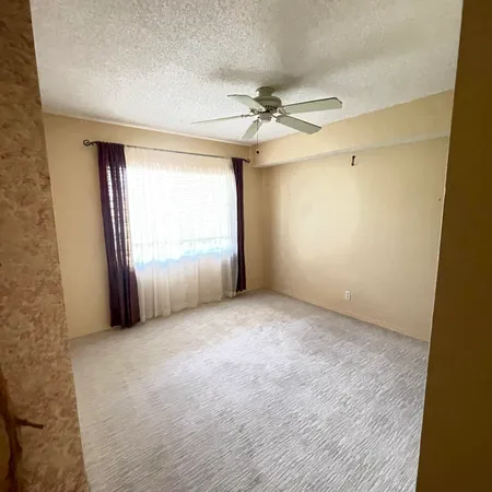 an empty room with windows and fan