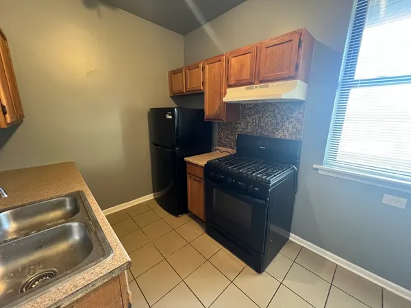 a kitchen with granite countertop a stove a refrigerator and a window