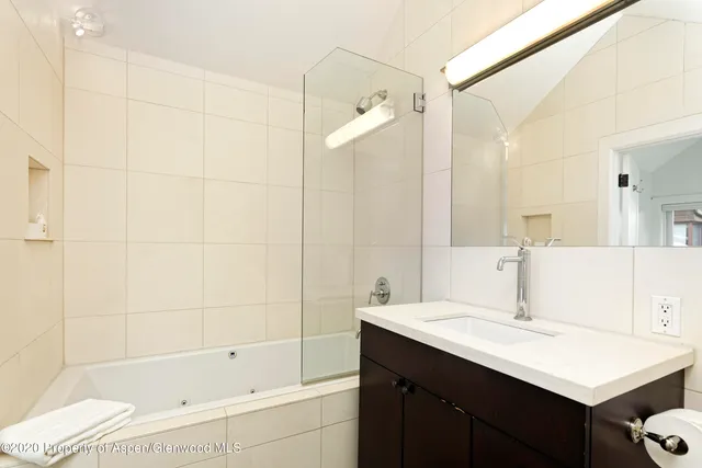 a bathroom with a bathtub shower sink vanity and a mirror