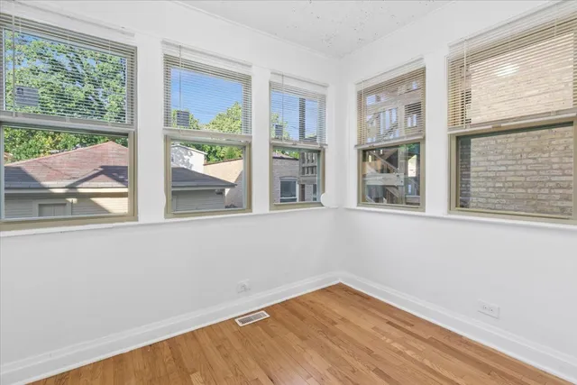 a view of empty room with wooden floor and fan