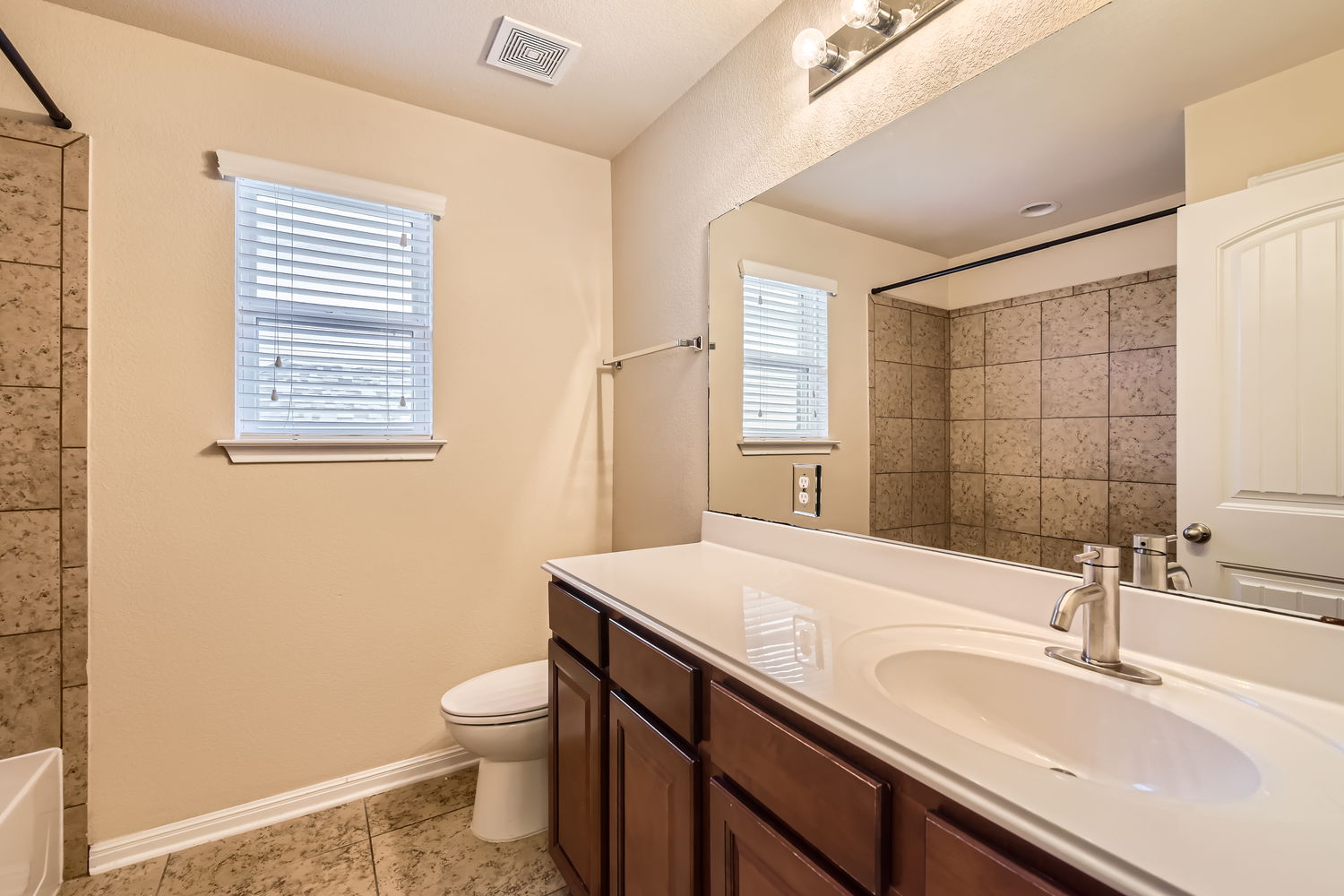 547 Stone View Trail, Unit 112 Austin, TX 78737 - Photo 18 of 28 a bathroom with a granite countertop sink toilet a large mirror and shower