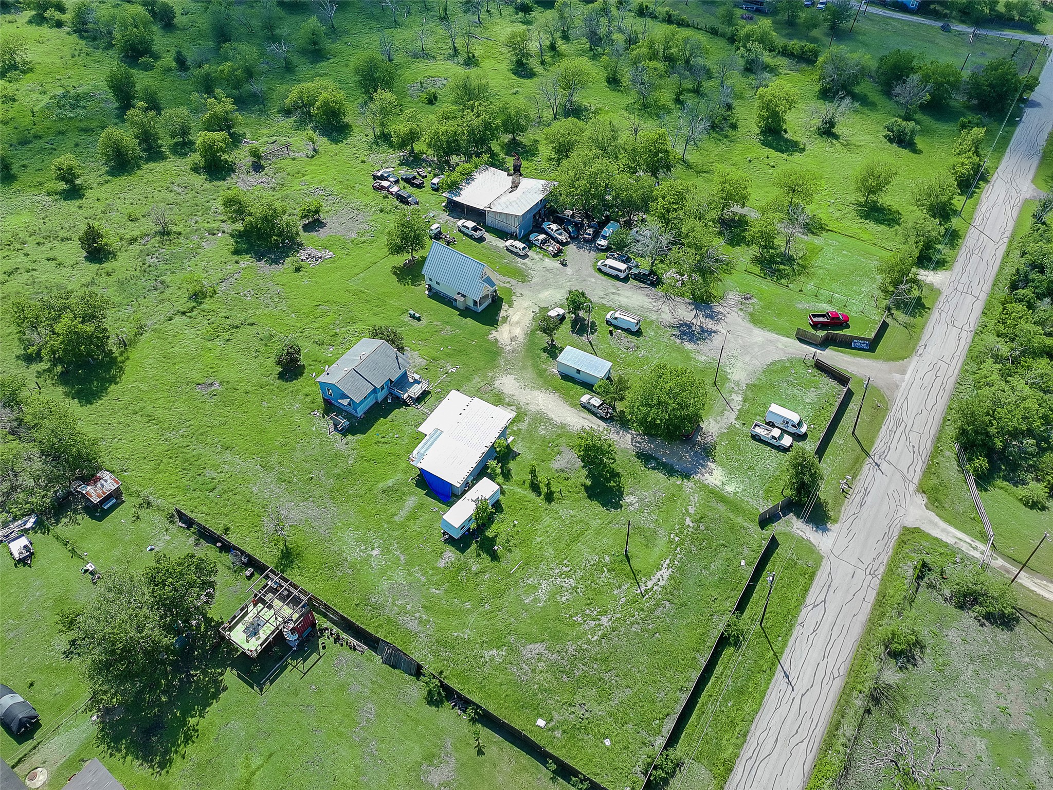 925 Long Hollow Road Dale, TX 78616 - Photo 6 of 26 Expansive green landscape featuring multiple structures, paved road frontage, and scattered mature trees