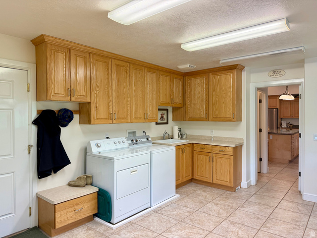 1133 Paris Canyon Road Paris, ID 83261 - Photo 30 of 75 Dedicated laundry area featuring extensive wood cabinetry, a utility sink, light-toned countertops, and durable tile flooring