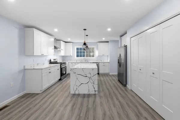a kitchen with stainless steel appliances kitchen island hardwood floor sink and stove
