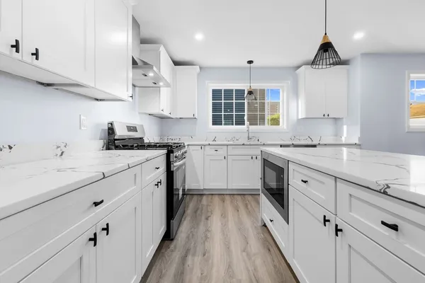 a kitchen with granite countertop a sink stove cabinets and wooden floor