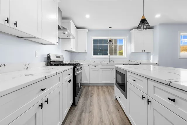 a kitchen with granite countertop a sink stove cabinets and wooden floor