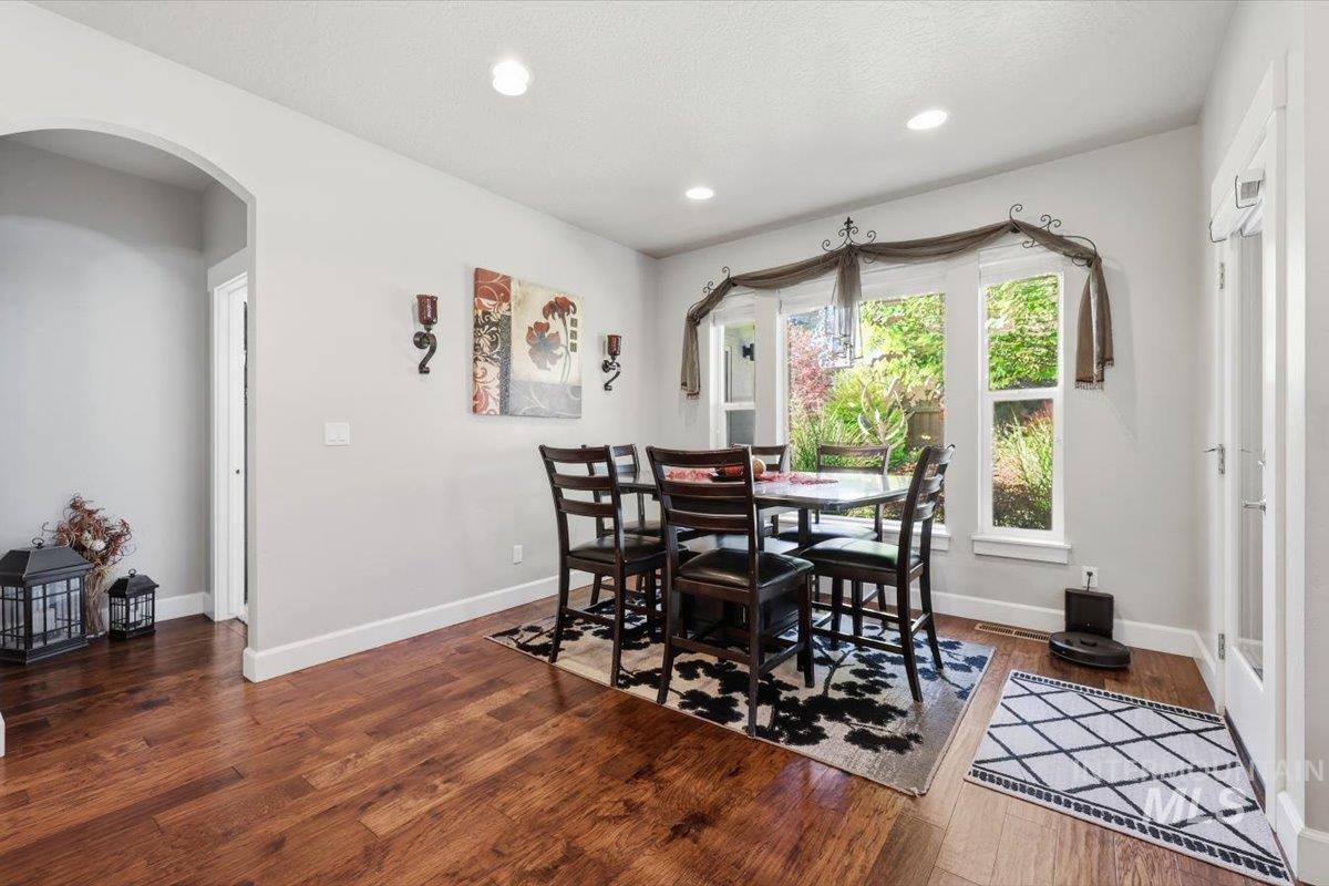 1303 West Brando Street Meridian, ID 83646 - Photo 17 of 49 Dining area featuring wood-finish flooring, recessed lighting, an arched doorway, and bay windows