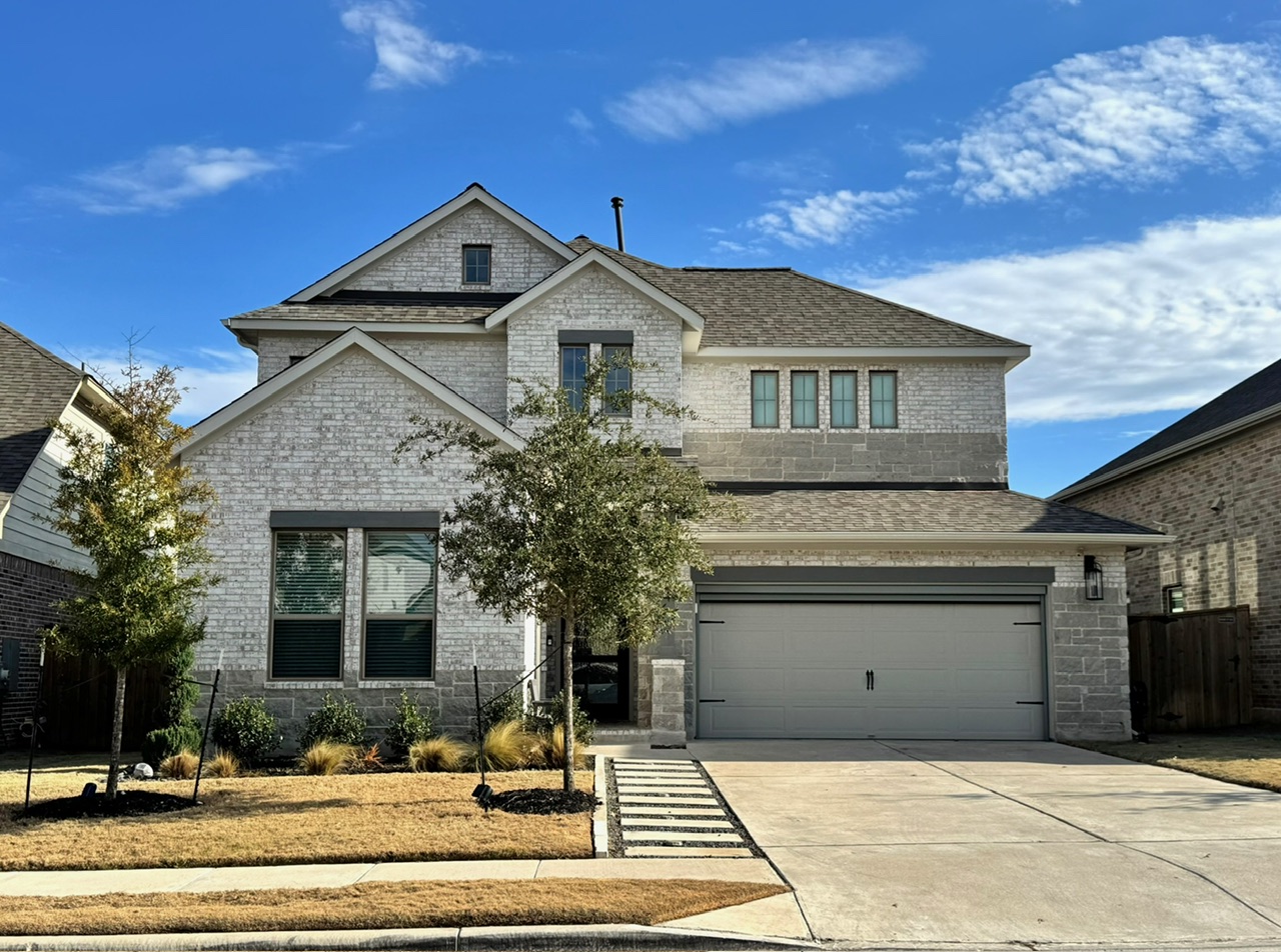 View of front of home with an attached garage, a shingled roof, driveway, and brick siding