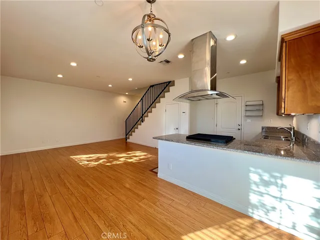 a kitchen with stainless steel appliances granite countertop a sink a stove and a wooden floors