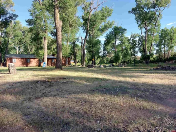 a view of a house with a big yard and large trees