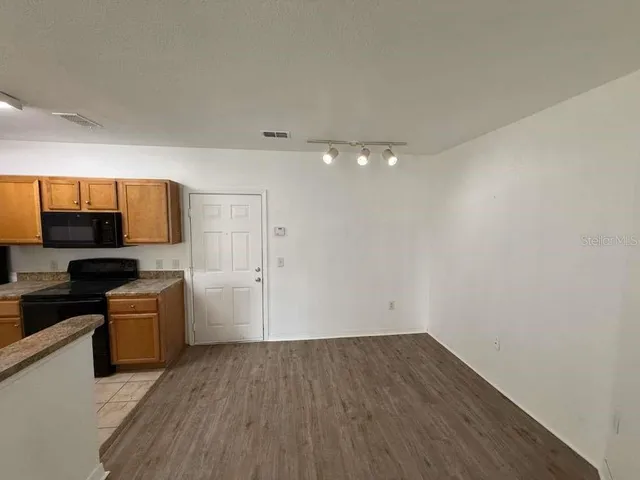 a view of a kitchen with a sink stove cabinets and empty room