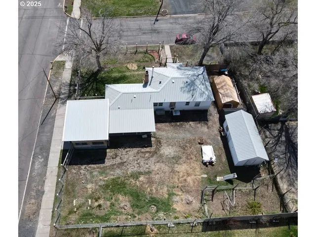 a backyard of a house with a large tree and wooden fence