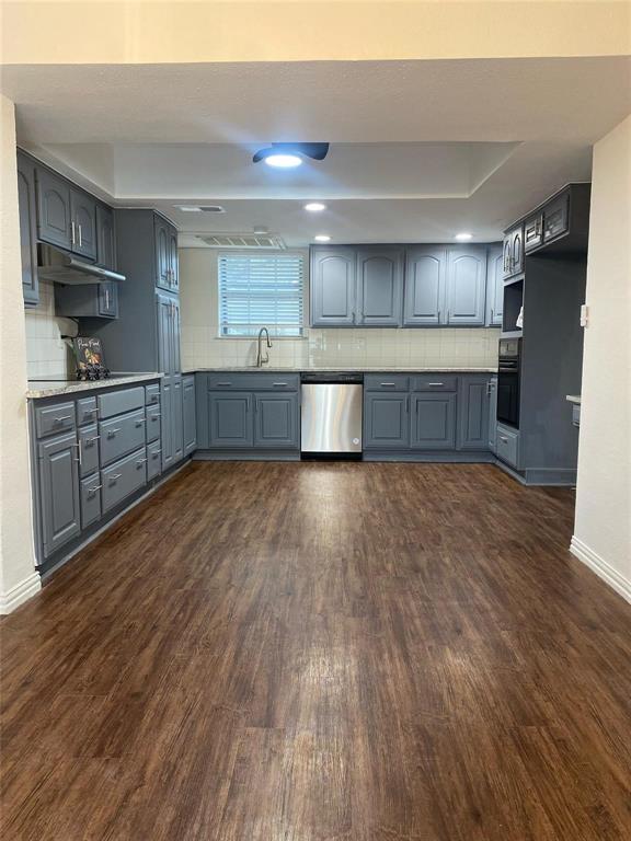 a large kitchen with stainless steel appliances and wooden floors