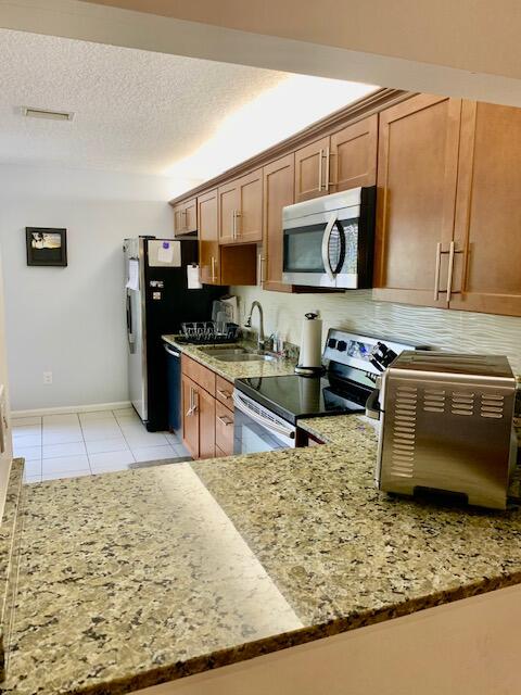 9256 Sable Ridge Circle, Unit B Boca Raton, FL 33428 - Photo 6 of 21 a kitchen with stainless steel appliances granite countertop a sink stove and microwave