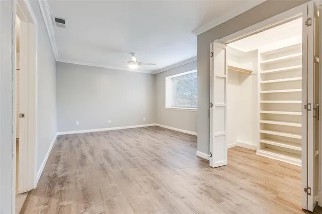 a view of empty room with wooden floor and fan