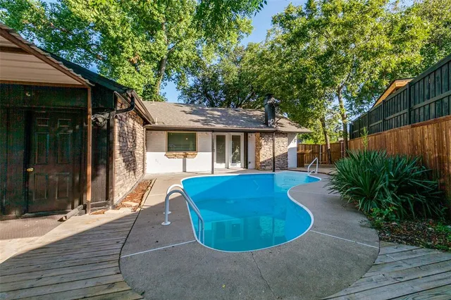 a view of a white house with a swimming pool and wooden fence