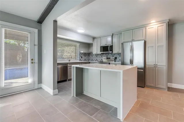 a kitchen with stainless steel appliances a sink a stove a refrigerator and cabinets