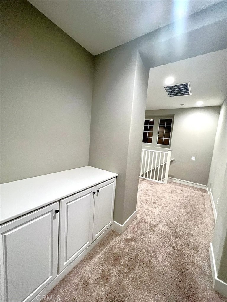 5177 Pomona Rincon Road Eastvale, CA 92880 - Photo 12 of 25 a hallway with white cabinets and wooden floor