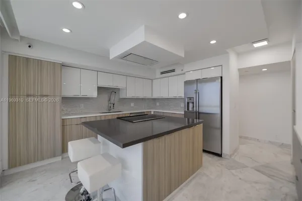 a large kitchen with stainless steel appliances a sink dishwasher a stove and a refrigerator with wooden floor