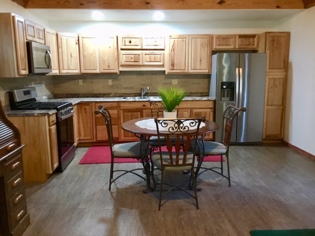 300 Collier Road Point Blank, TX 77364 - Photo 19 of 49 a kitchen with stainless steel appliances granite countertop a refrigerator a stove a sink dishwasher and chairs with wooden floor
