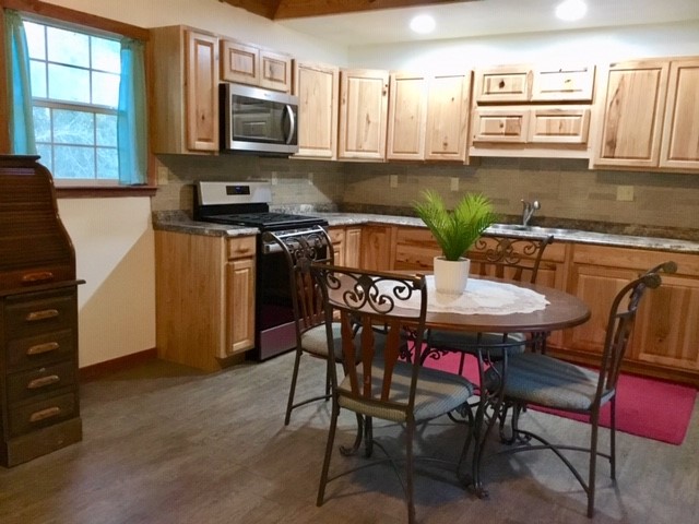 300 Collier Road Point Blank, TX 77364 - Photo 44 of 49 a kitchen with stainless steel appliances granite countertop a stove a sink a microwave a dining table and chairs with wooden floor