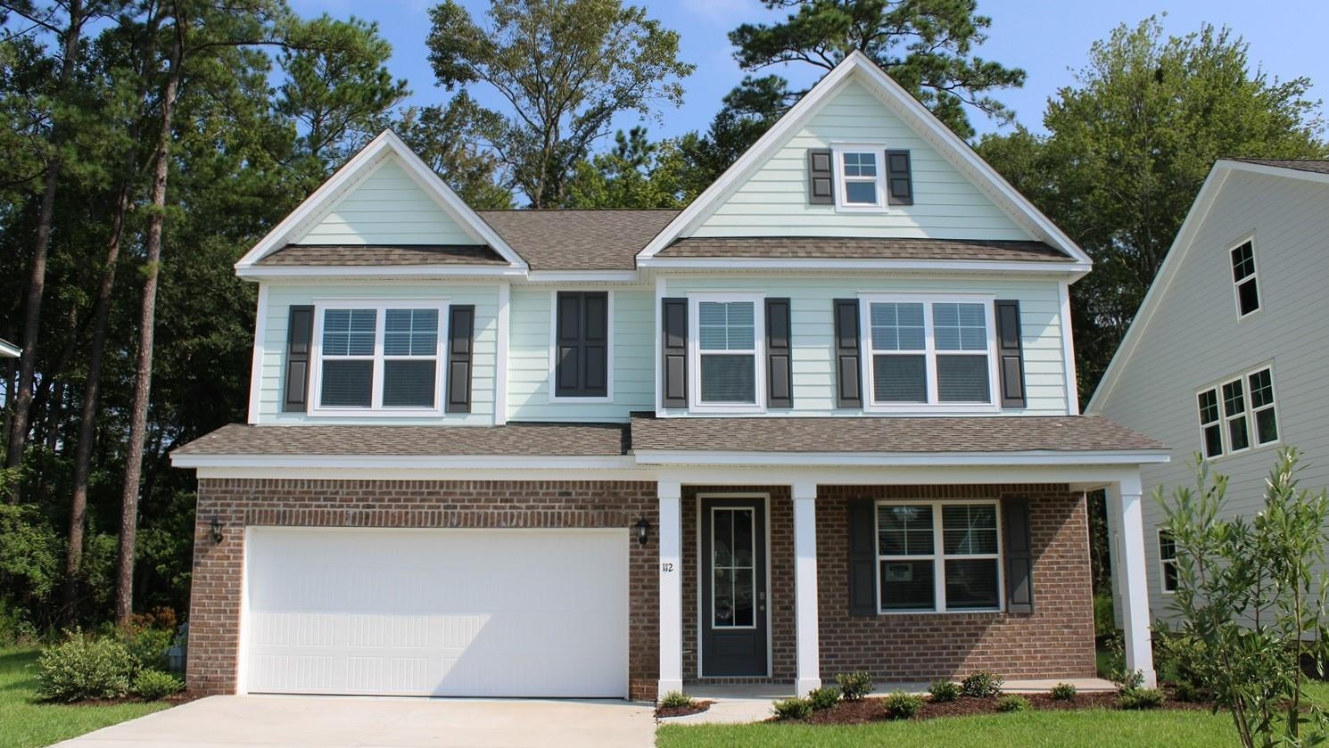 View of front facade with a porch, roof with shingles, and brick siding