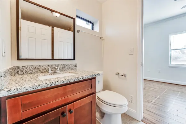 a bathroom with a granite countertop sink toilet and mirror