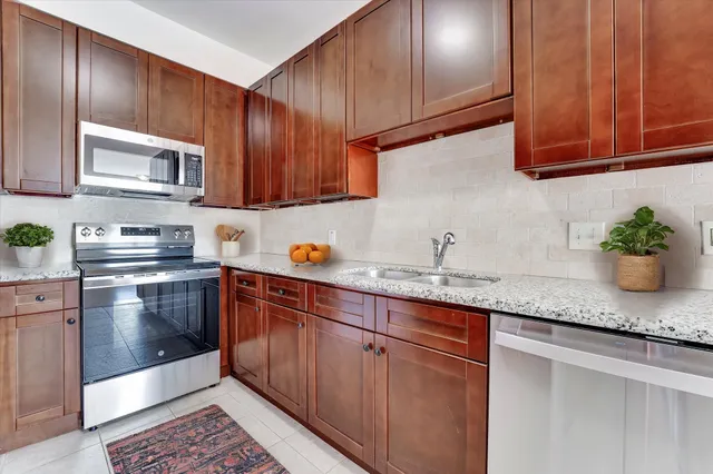 a kitchen with granite countertop stainless steel appliances wooden cabinets and a sink