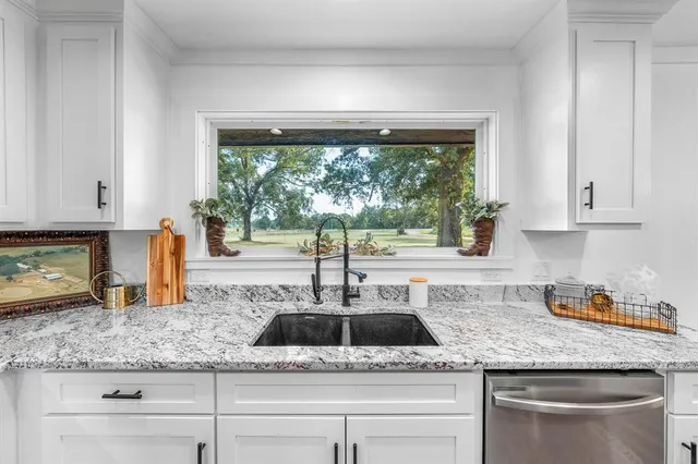 a kitchen with granite countertop white cabinets and window