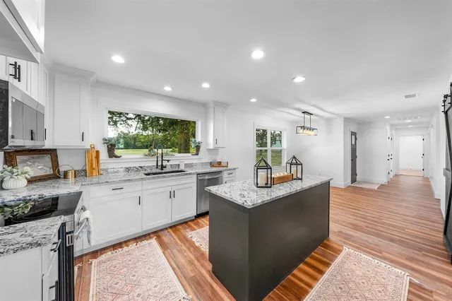 a kitchen with stainless steel appliances kitchen island granite countertop a sink and cabinets