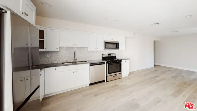 a kitchen with granite countertop a sink cabinets and stainless steel appliances