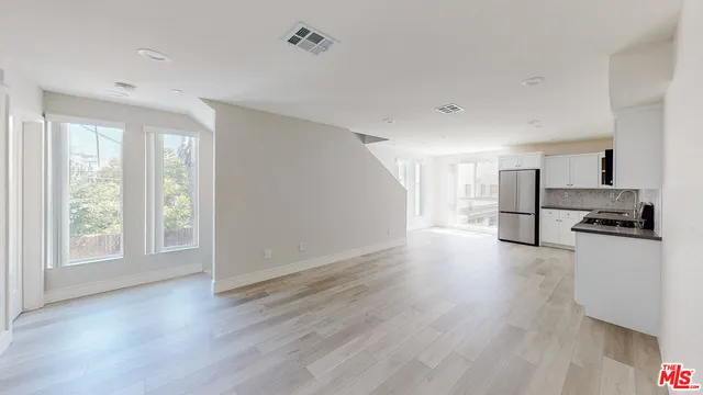 a view of a kitchen with wooden floor electronic appliances and window