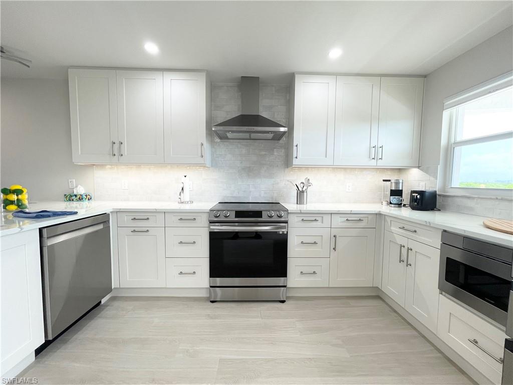 12945 Vanderbilt Drive, Unit 403 Naples, FL 34110 - Photo 19 of 42 a kitchen with granite countertop white cabinets and white appliances