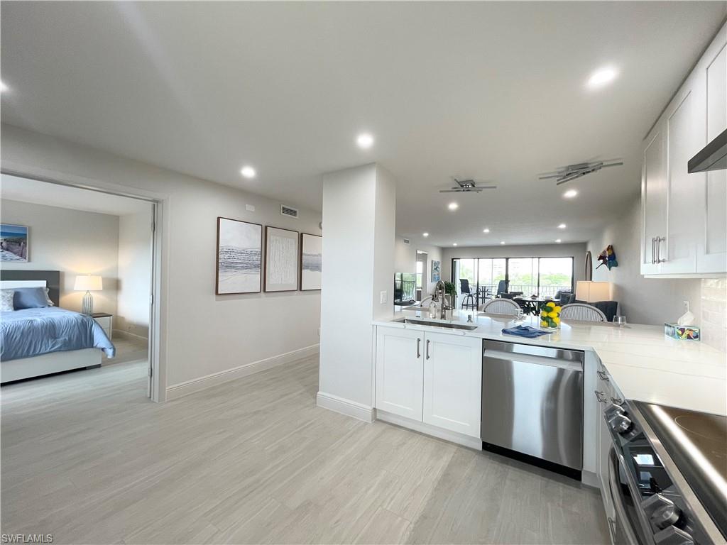 12945 Vanderbilt Drive, Unit 403 Naples, FL 34110 - Photo 20 of 42 a kitchen with stainless steel appliances granite countertop a sink and stove top oven