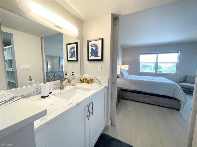 a en suite bathroom with a granite countertop sink and a large mirror