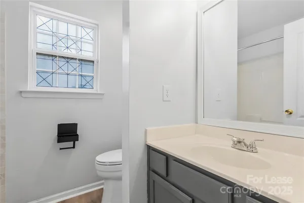 a bathroom with a granite countertop sink a toilet and a window