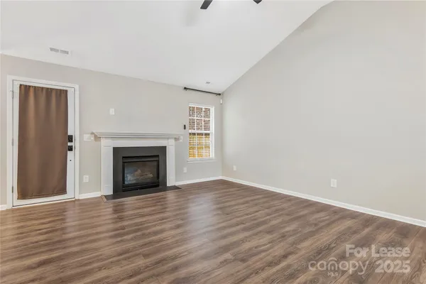 a view of empty room with wooden floor and fireplace