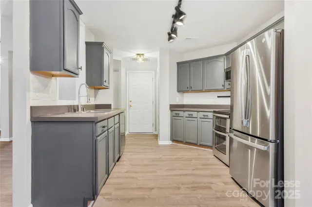a kitchen with granite countertop a refrigerator stove and sink